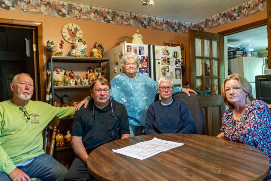 Clara Riley stands with her family members around their dining room table.